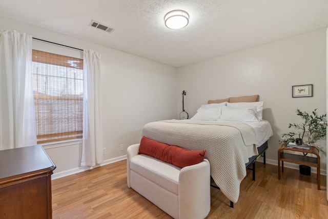 bedroom featuring light hardwood / wood-style flooring and a textured ceiling