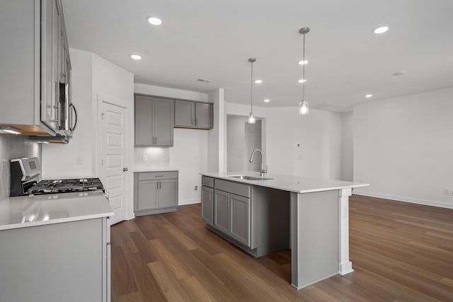 kitchen with an island with sink, stainless steel appliances, sink, and hanging light fixtures