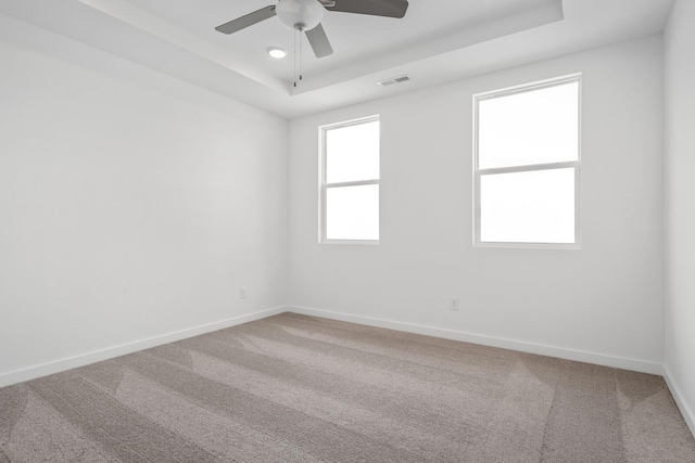 carpeted spare room with ceiling fan and a tray ceiling