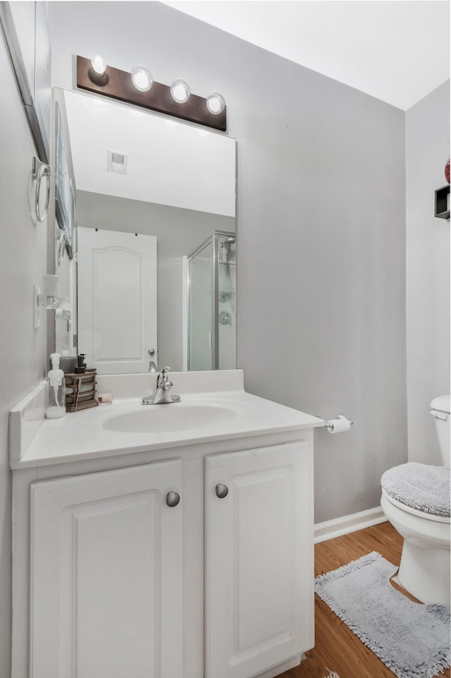 bathroom featuring vanity, wood-type flooring, toilet, and walk in shower