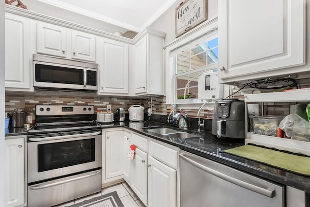 kitchen featuring sink, tasteful backsplash, ornamental molding, stainless steel appliances, and white cabinets