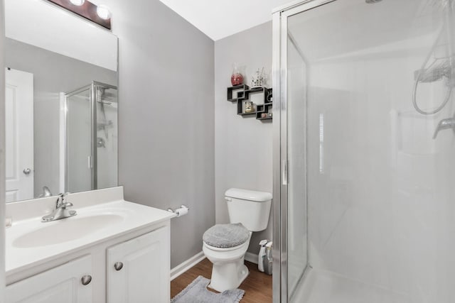 bathroom with a shower with door, vanity, wood-type flooring, and toilet