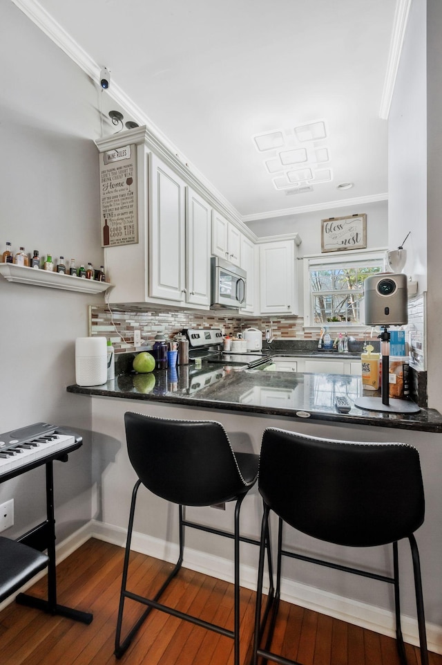 kitchen featuring decorative backsplash, a breakfast bar area, stainless steel appliances, and white cabinets