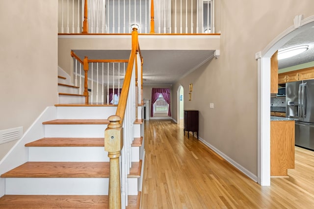 stairs with wood-type flooring and ornamental molding