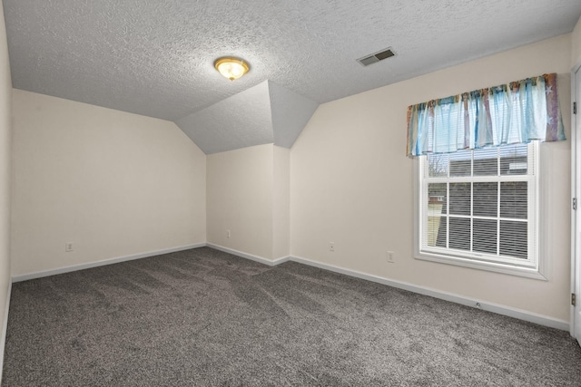 additional living space featuring vaulted ceiling, a textured ceiling, and dark colored carpet