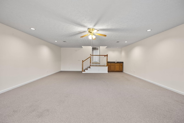 unfurnished room with ceiling fan, light carpet, and a textured ceiling