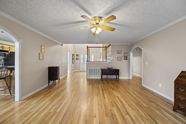 unfurnished living room featuring a textured ceiling, light hardwood / wood-style flooring, ornamental molding, and ceiling fan