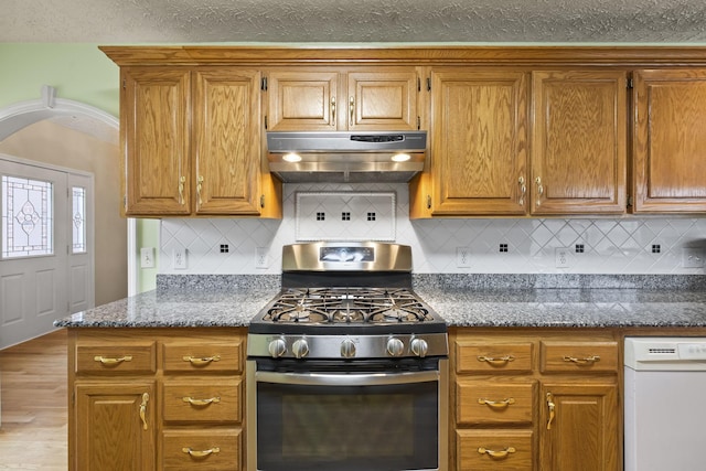 kitchen with stainless steel gas range oven, tasteful backsplash, a textured ceiling, white dishwasher, and stone counters