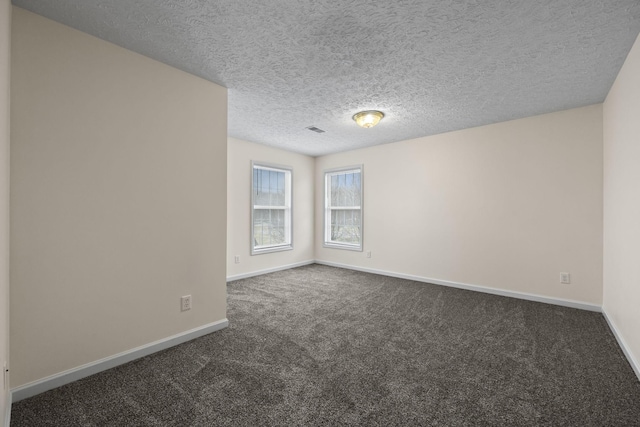 spare room with a textured ceiling and dark carpet