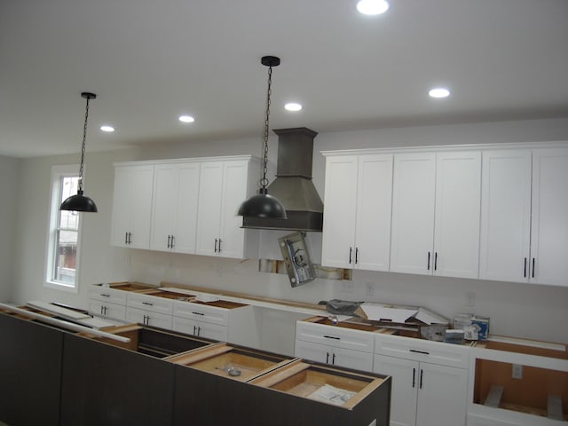 kitchen with pendant lighting, white cabinetry, a kitchen island, and custom range hood