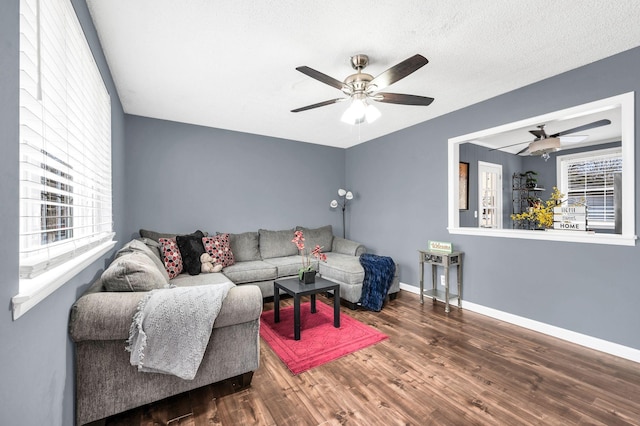 living room with dark wood-type flooring, ceiling fan, and a textured ceiling