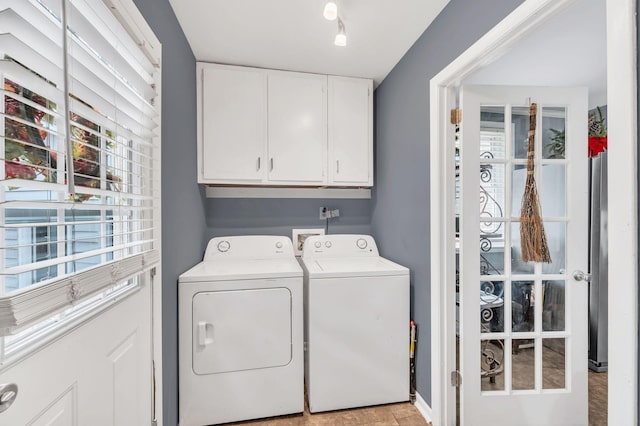 clothes washing area featuring washing machine and dryer and cabinets