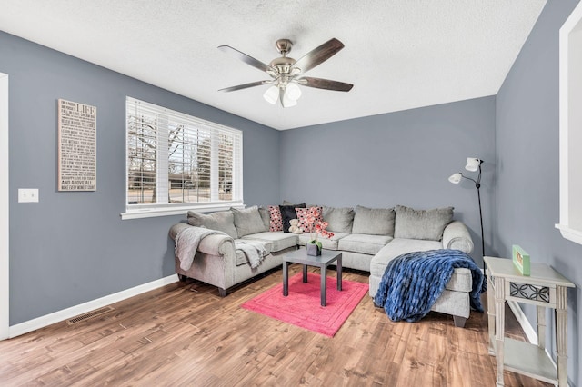 living room with hardwood / wood-style floors, a textured ceiling, and ceiling fan