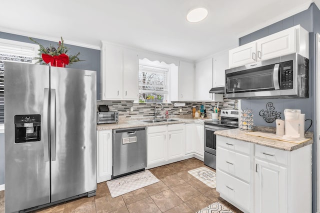 kitchen featuring sink, light stone counters, appliances with stainless steel finishes, decorative backsplash, and white cabinets