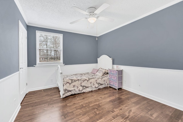 bedroom with ceiling fan, crown molding, dark wood-type flooring, and a textured ceiling