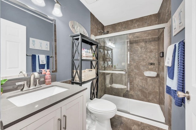 bathroom featuring vanity, a shower with shower door, and toilet