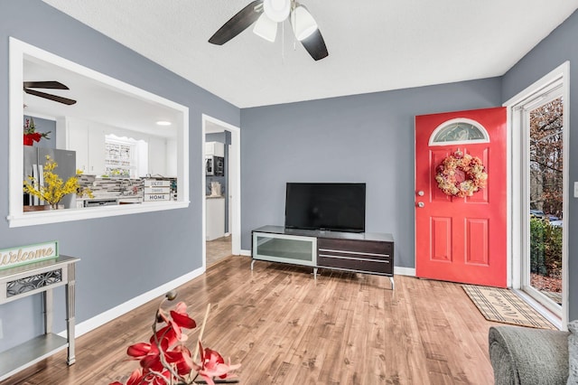 living room featuring a textured ceiling, light hardwood / wood-style floors, and ceiling fan