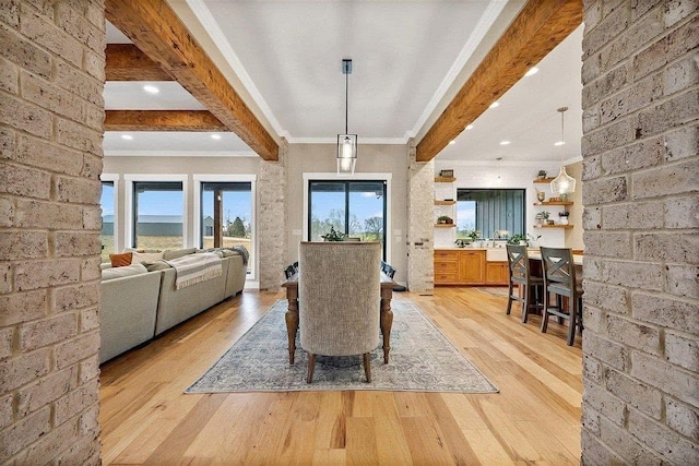 dining room with ornamental molding, brick wall, beam ceiling, and light hardwood / wood-style floors