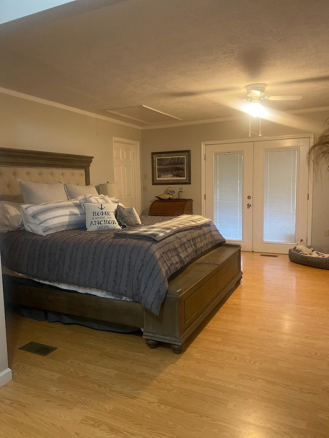 bedroom featuring french doors, crown molding, a textured ceiling, and light wood-type flooring