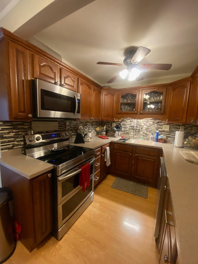 kitchen with sink, backsplash, ceiling fan, stainless steel appliances, and light hardwood / wood-style flooring