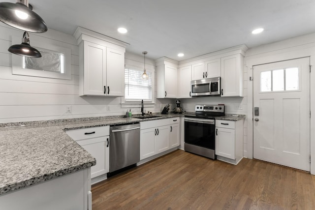 kitchen with hanging light fixtures, stainless steel appliances, sink, and white cabinets