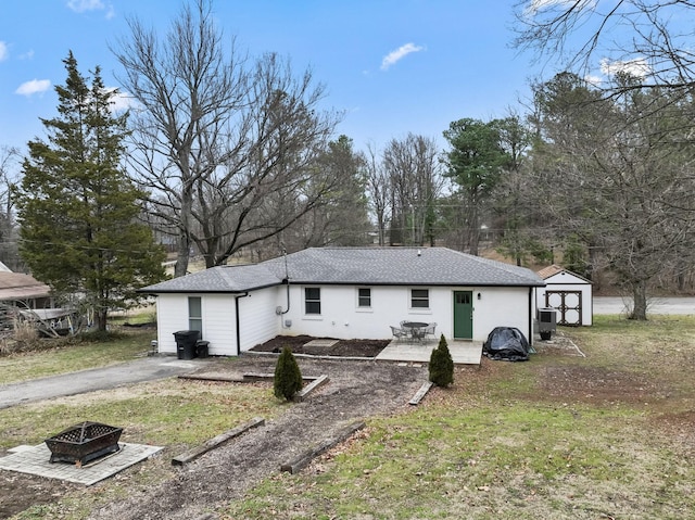 rear view of house featuring a shed, a patio area, a fire pit, and a lawn