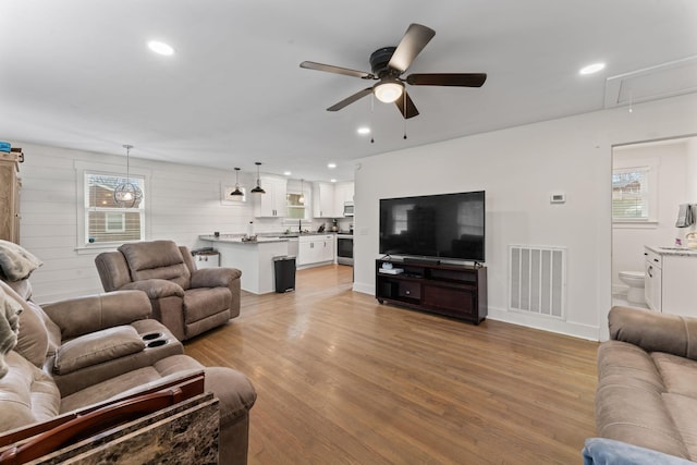 living room featuring ceiling fan, sink, and light hardwood / wood-style floors