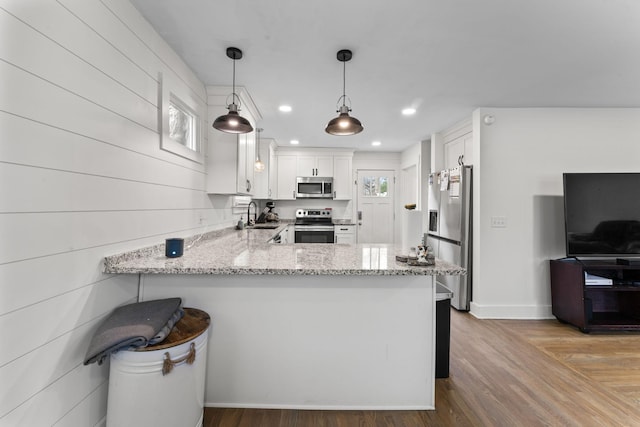 kitchen with sink, white cabinetry, hanging light fixtures, kitchen peninsula, and stainless steel appliances