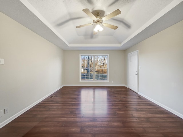 spare room featuring dark hardwood / wood-style floors, a textured ceiling, a raised ceiling, and ceiling fan