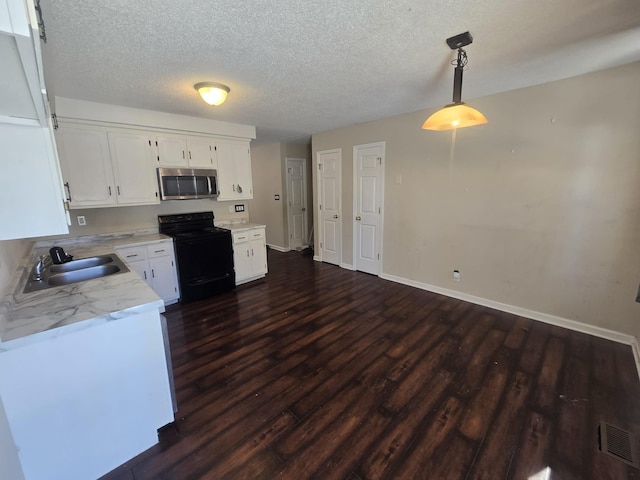 kitchen featuring black / electric stove, a sink, light countertops, stainless steel microwave, and decorative light fixtures