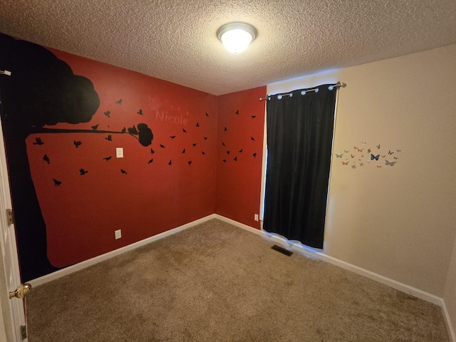 carpeted empty room with visible vents, a textured ceiling, and baseboards