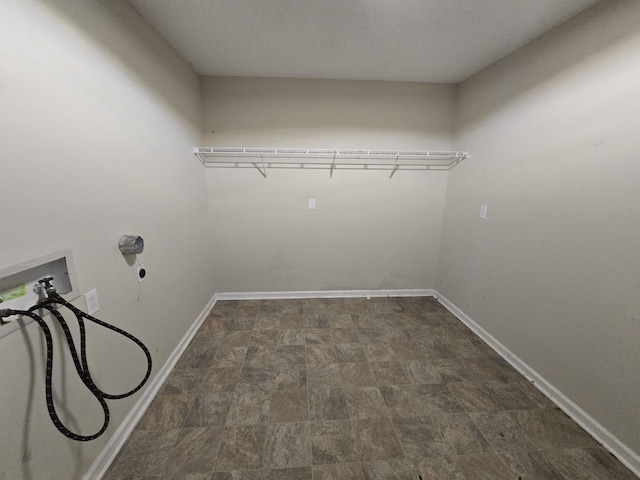 clothes washing area with laundry area, stone finish flooring, hookup for a washing machine, and baseboards