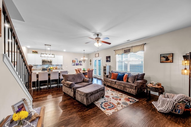 living room with dark hardwood / wood-style flooring and ceiling fan with notable chandelier