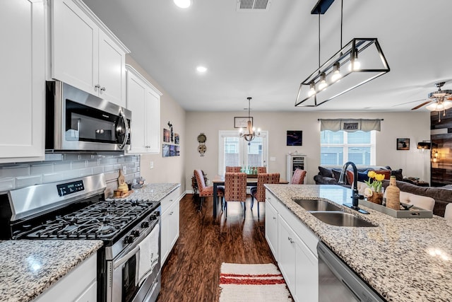 kitchen featuring white cabinetry, stainless steel appliances, sink, and hanging light fixtures