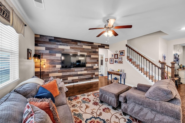 living room featuring hardwood / wood-style flooring, ceiling fan, and wooden walls