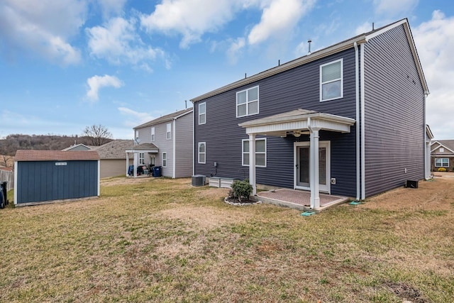 back of house featuring a patio area, a lawn, central AC, and a storage unit