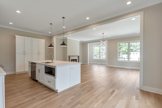 kitchen with built in microwave, sink, a kitchen island with sink, and decorative light fixtures