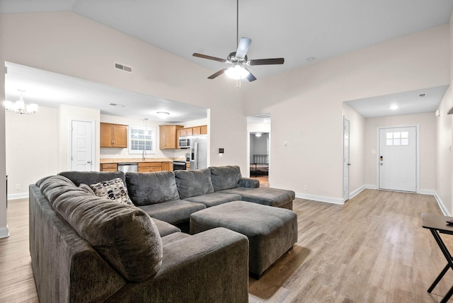 living room featuring high vaulted ceiling, sink, ceiling fan with notable chandelier, and light hardwood / wood-style floors