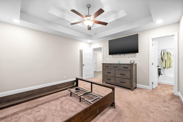 carpeted bedroom with ceiling fan and a tray ceiling