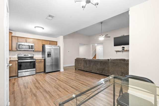 kitchen featuring stainless steel appliances, ceiling fan, and light wood-type flooring