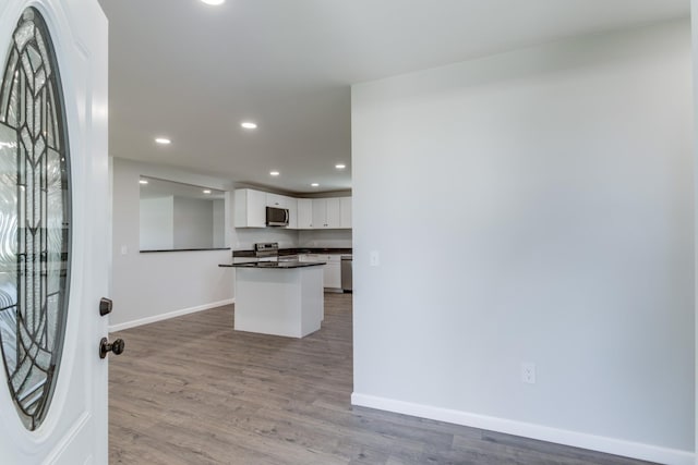 kitchen with stainless steel appliances, kitchen peninsula, hardwood / wood-style floors, and white cabinets