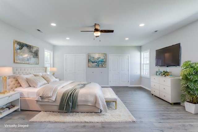 bedroom featuring two closets, wood-type flooring, and ceiling fan