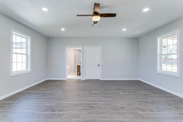 empty room with ceiling fan, plenty of natural light, and hardwood / wood-style floors