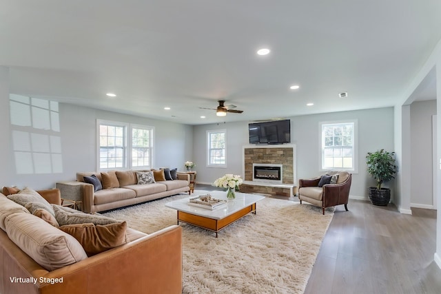 living room with ceiling fan, a wealth of natural light, a fireplace, and light hardwood / wood-style floors