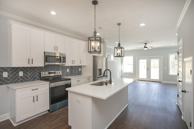 kitchen with pendant lighting, sink, white cabinets, a kitchen island with sink, and stainless steel appliances