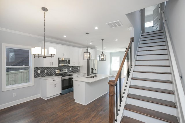 kitchen with sink, decorative light fixtures, a center island with sink, appliances with stainless steel finishes, and white cabinets