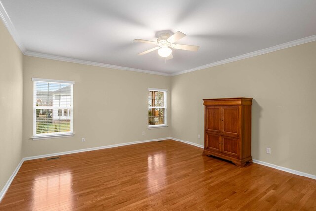 empty room featuring crown molding, wood-type flooring, and ceiling fan