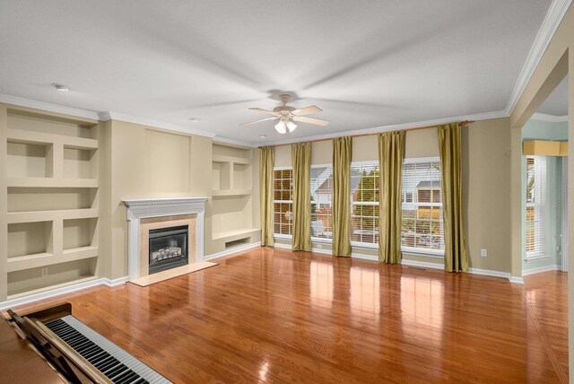 unfurnished living room with ornamental molding, a premium fireplace, hardwood / wood-style floors, and built in features