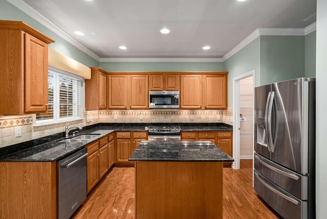 kitchen with sink, a center island, dark stone counters, and appliances with stainless steel finishes