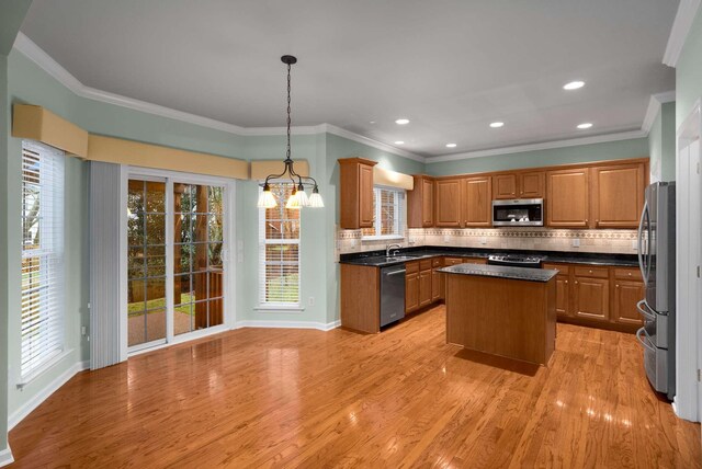 kitchen featuring pendant lighting, stainless steel appliances, a kitchen island, and light wood-type flooring